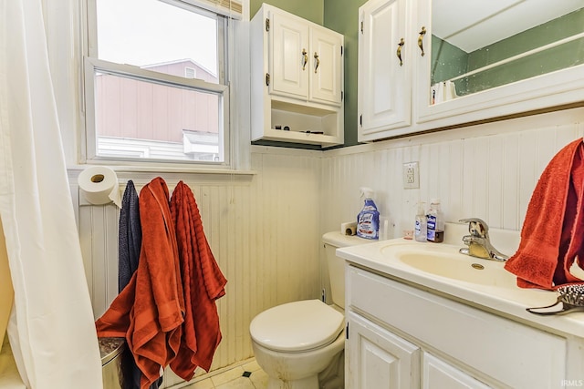 bathroom with vanity, a shower with curtain, a wainscoted wall, tile patterned flooring, and toilet