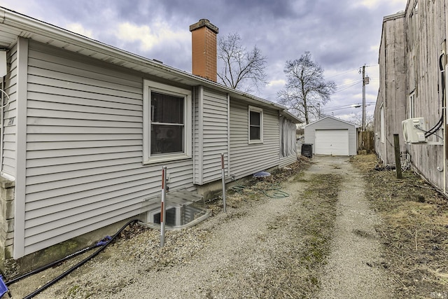 view of property exterior featuring fence, dirt driveway, a chimney, a garage, and an outbuilding