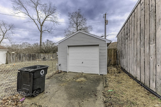 detached garage with concrete driveway and fence