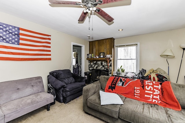 living area featuring a fireplace, ceiling fan, and carpet flooring