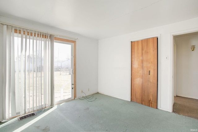 spare room with visible vents, plenty of natural light, and carpet flooring