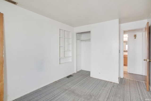 unfurnished bedroom with visible vents, carpet, and a closet