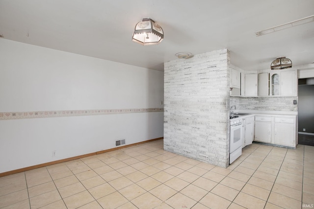 kitchen featuring visible vents, white range with gas cooktop, light countertops, white cabinetry, and backsplash