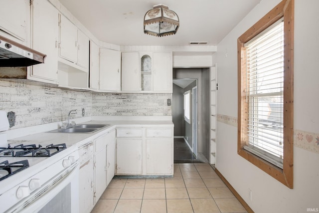 kitchen with visible vents, gas range gas stove, light tile patterned flooring, a sink, and under cabinet range hood