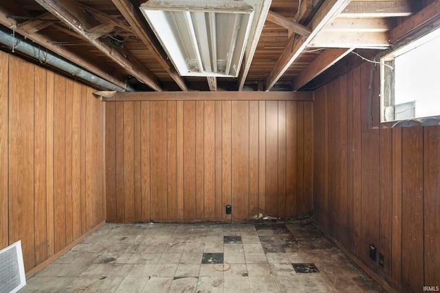 basement featuring tile patterned floors, wooden walls, and visible vents