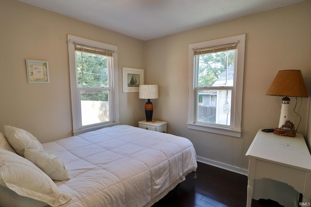 bedroom with baseboards, multiple windows, and dark wood finished floors