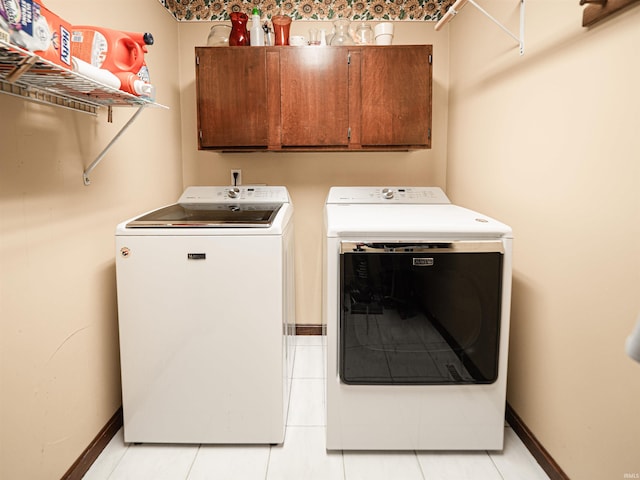 clothes washing area featuring cabinet space, baseboards, and separate washer and dryer