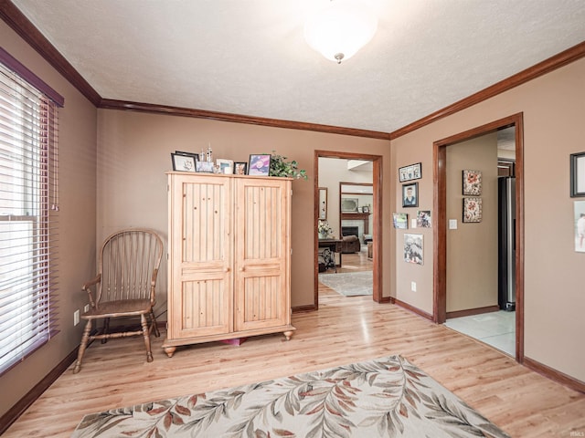 living area featuring light wood-style flooring, a healthy amount of sunlight, and ornamental molding