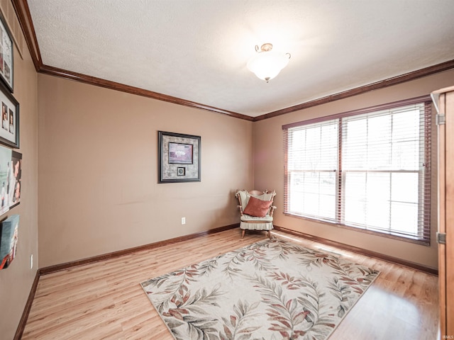 living area featuring light wood-style flooring, a textured ceiling, crown molding, and baseboards