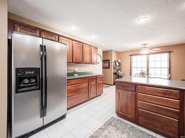 kitchen with a textured ceiling, light tile patterned floors, stainless steel refrigerator with ice dispenser, and ceiling fan