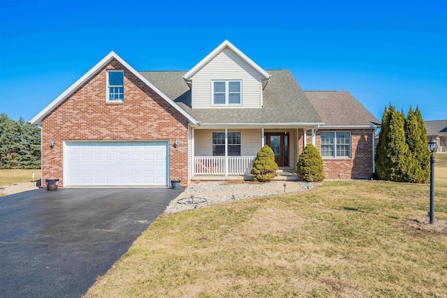 view of front of house with brick siding, a shingled roof, a porch, a front yard, and driveway