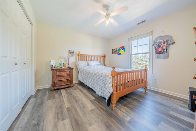 bedroom with visible vents, ceiling fan, baseboards, wood finished floors, and a closet