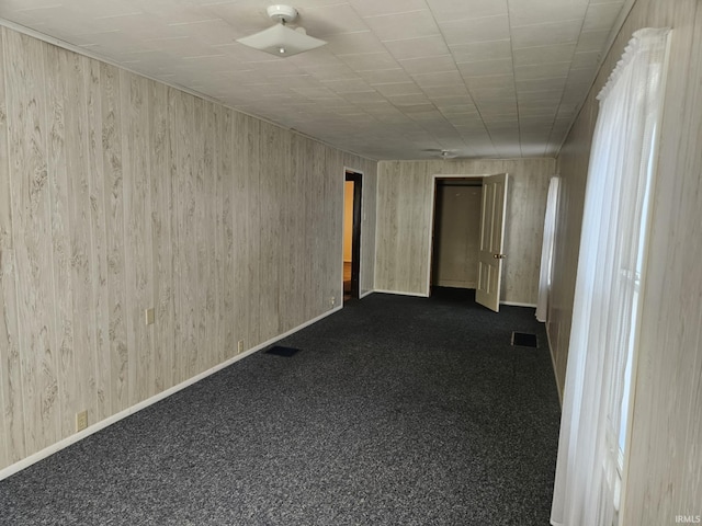 empty room with visible vents, baseboards, and dark carpet