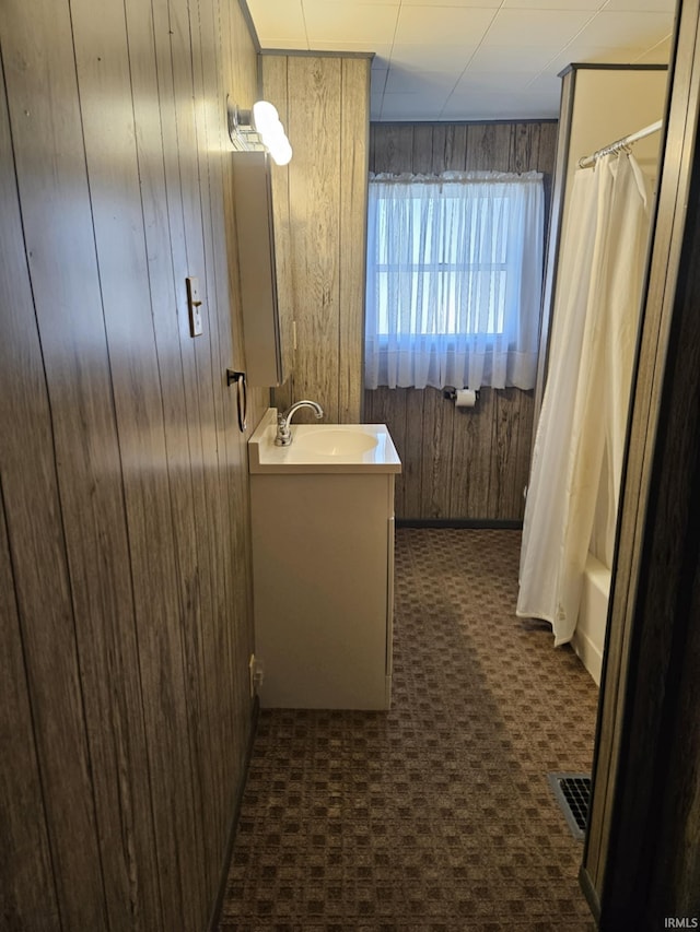 full bath featuring visible vents, wood walls, vanity, and shower / bath combo