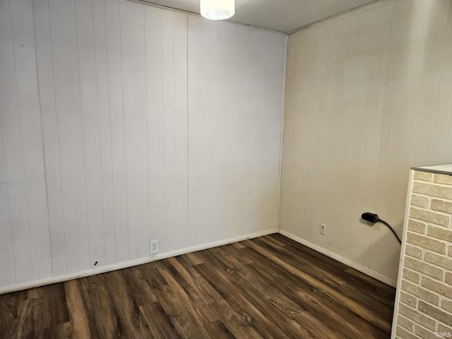 spare room with baseboards and dark wood-style floors