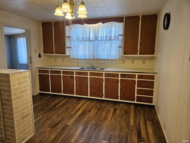 kitchen featuring a chandelier, light countertops, dark wood-type flooring, and a sink