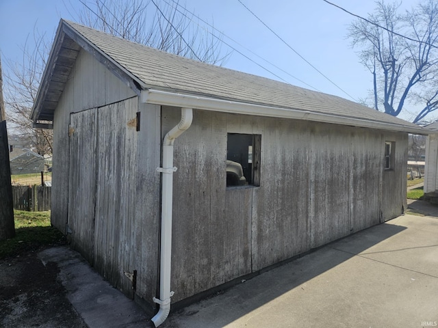 view of side of property featuring roof with shingles, an outdoor structure, and fence