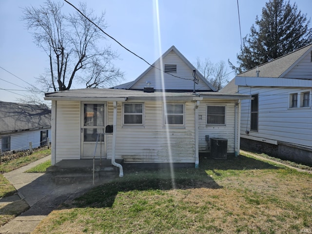 back of house with central air condition unit and a yard