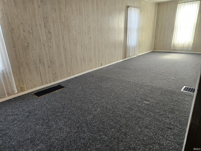 empty room featuring visible vents, carpet floors, and baseboards