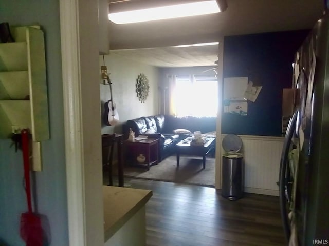 hall featuring a wainscoted wall and dark wood-style flooring