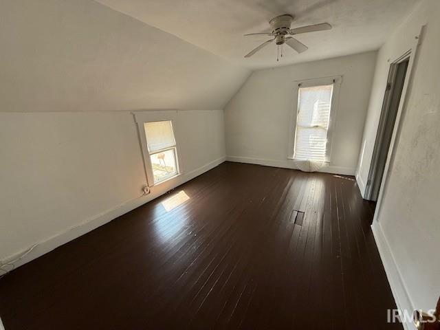 additional living space with vaulted ceiling, baseboards, dark wood-style flooring, and a wealth of natural light