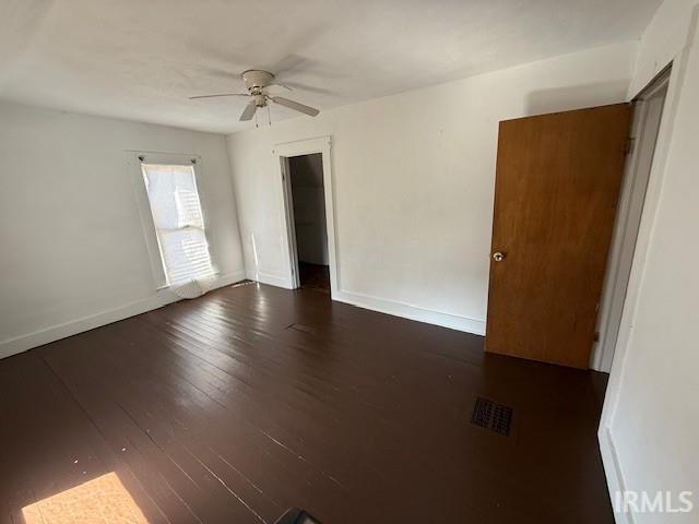 spare room with hardwood / wood-style flooring, a ceiling fan, baseboards, and visible vents