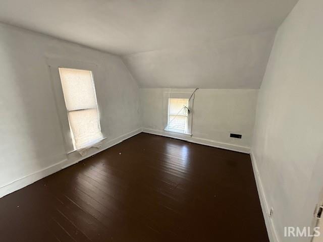 additional living space with baseboards, lofted ceiling, and hardwood / wood-style floors