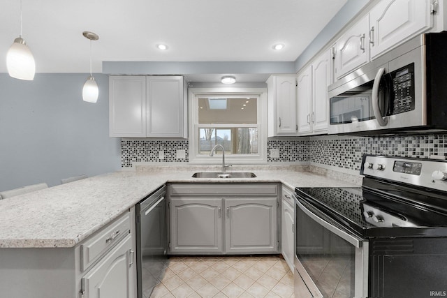 kitchen featuring tasteful backsplash, light tile patterned floors, appliances with stainless steel finishes, a peninsula, and a sink