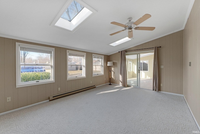 carpeted empty room featuring a ceiling fan, lofted ceiling with skylight, a healthy amount of sunlight, and baseboard heating