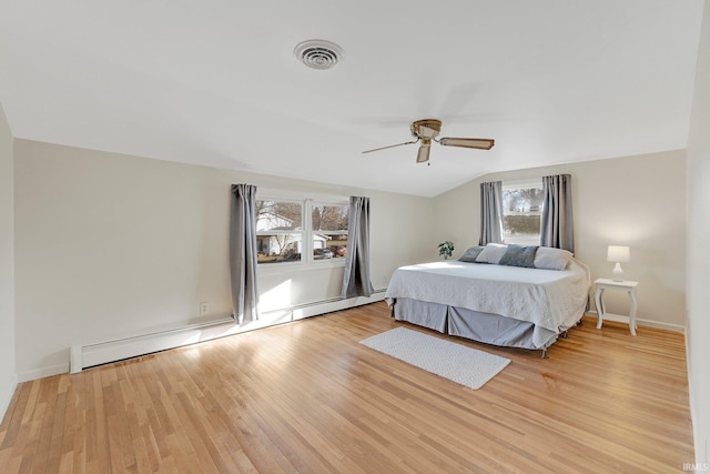 bedroom featuring light wood finished floors, visible vents, a baseboard heating unit, vaulted ceiling, and a ceiling fan