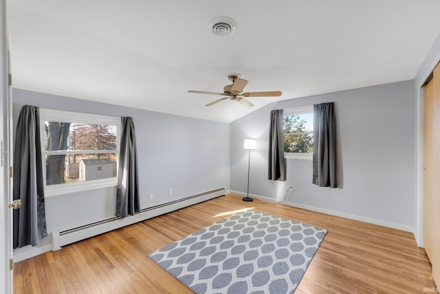 unfurnished room featuring visible vents, a baseboard heating unit, wood finished floors, lofted ceiling, and ceiling fan