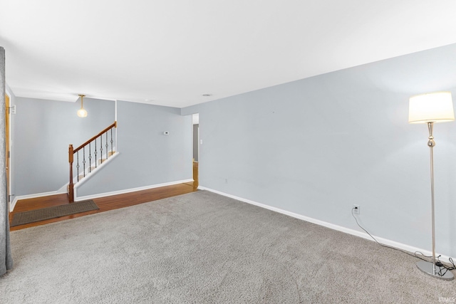 unfurnished living room featuring baseboards, carpet, and stairs