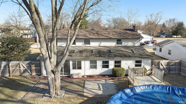 rear view of property with fence and a shingled roof