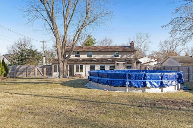 rear view of property with a yard, a fenced in pool, a chimney, and fence