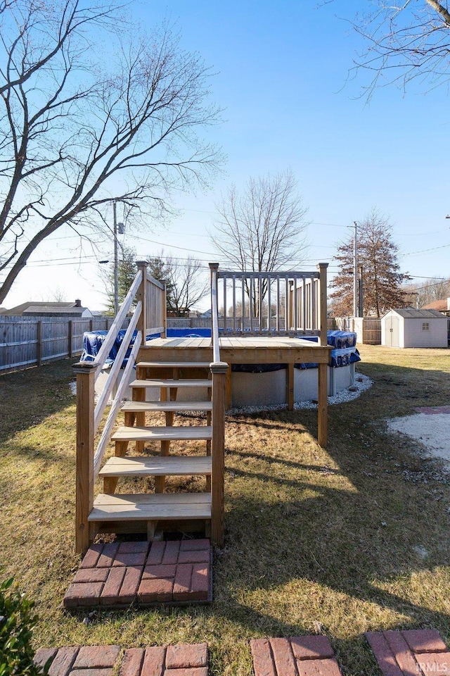 deck with an outbuilding, fence, a shed, a yard, and stairs