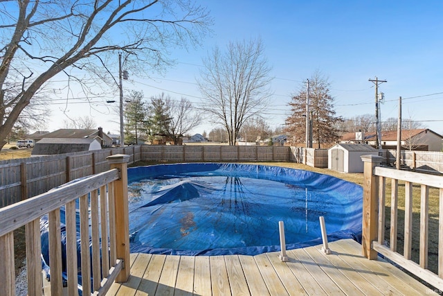 view of swimming pool with a wooden deck, a storage unit, an outdoor structure, and a fenced backyard