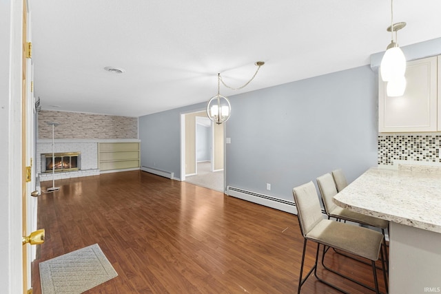 dining space featuring baseboard heating, a fireplace, dark wood-type flooring, and baseboards