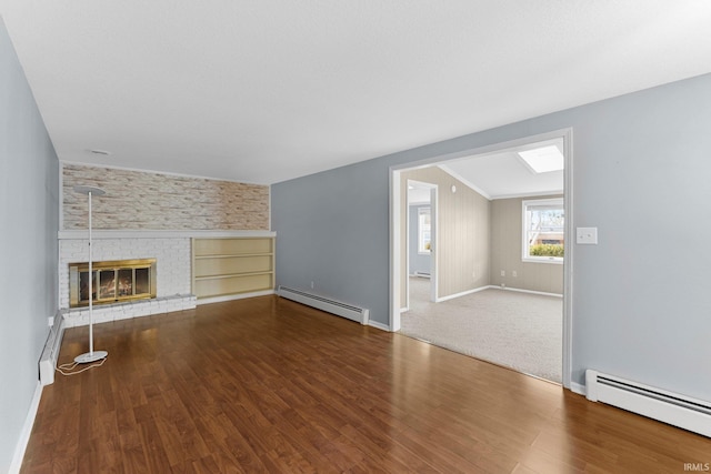 unfurnished living room featuring baseboard heating, wood finished floors, and a fireplace