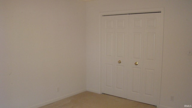 spare room with baseboards and light carpet