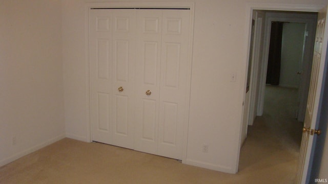 unfurnished bedroom featuring a closet, light colored carpet, and baseboards