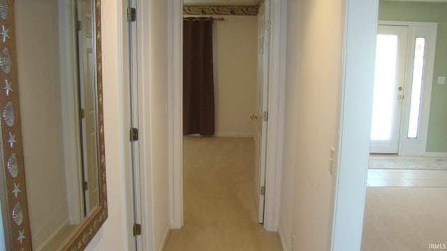 hallway featuring light tile patterned floors and light colored carpet