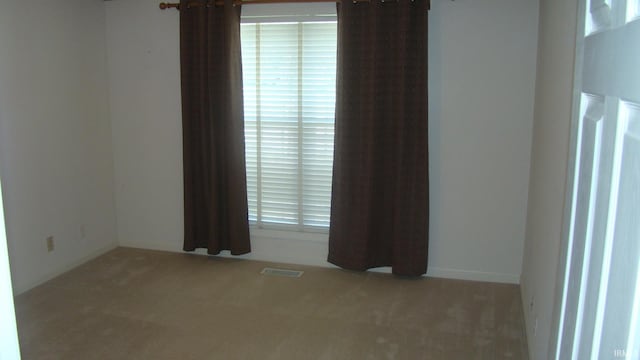 carpeted empty room featuring visible vents