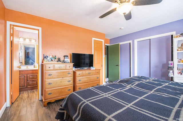 bedroom featuring a sink, multiple closets, wood finished floors, and a ceiling fan