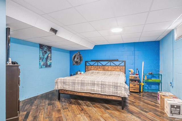 bedroom featuring visible vents, wood-type flooring, and concrete block wall