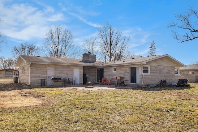 rear view of property featuring a chimney, a fire pit, stone siding, a patio area, and a lawn