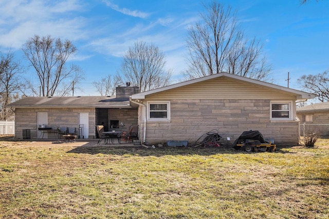 back of property with a patio area, stone siding, and a lawn