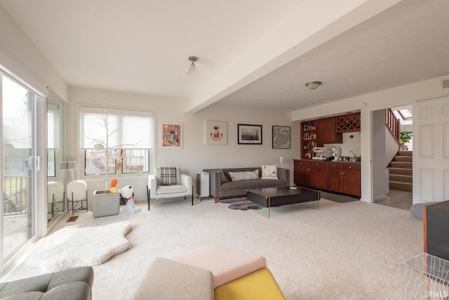 living room with beam ceiling, bar, stairs, and carpet