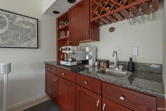 kitchen with open shelves, dark stone counters, baseboards, and a sink