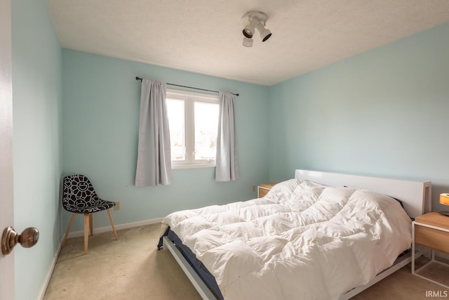 carpeted bedroom with a textured ceiling and baseboards