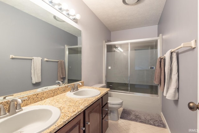 full bathroom featuring double vanity, toilet, a textured ceiling, and a sink